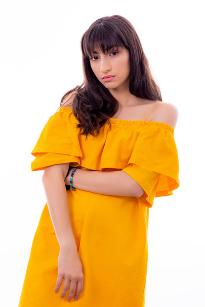 Portrait of Attractive Young Female Model. La fille pose avec une robe jaune dans un studio avec un fond blanc
. - Photo, image