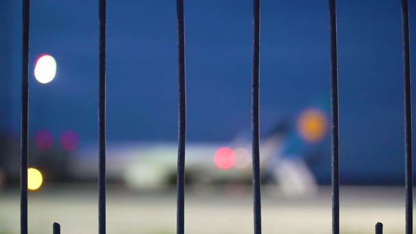 Defocused widok na samolot zaparkowany na bramie lotniska. Wózek bezpieczeństwa przechodzi przez - Materiał filmowy, wideo