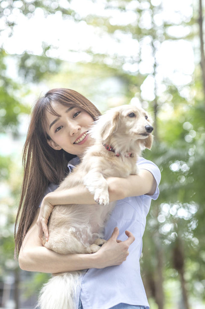 Jovem mulher asiática com cão na rua
 - Foto, Imagem