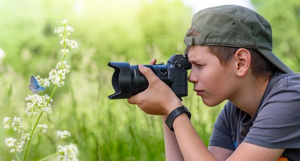 Junge hält Digitalkamera und schießt Schmetterling auf die Wildblume - Foto, Bild