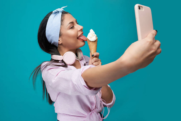 Stylish girl eating tasty ice cream and taking selfie - Foto, afbeelding