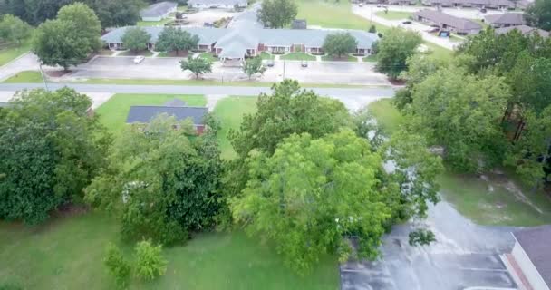 Veduta aerea di una tipica area suburbana americana che mostra un mix di spazi residenziali, commerciali e naturali collegati da vialetti di accesso a strade e strade di campagna con fasce di spazi per parcheggi, prati, alberi, cespugli e altre piantagioni
. - Filmati, video