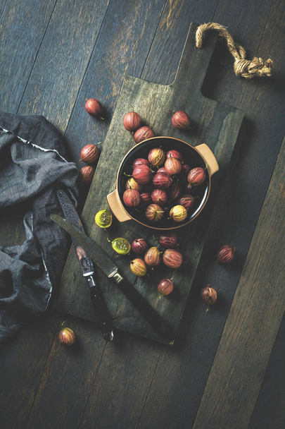 Fresh gooseberries on dark wooden board, top view - Φωτογραφία, εικόνα