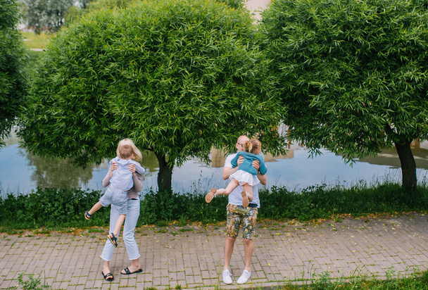 Jonge ouders draaien rond, wervelende met kinderen in Park. - Foto, afbeelding