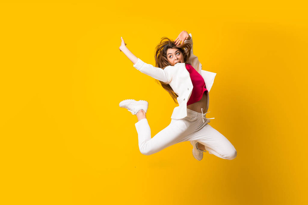 Молода жінка стрибає через ізольовану жовту стіну
 - Фото, зображення