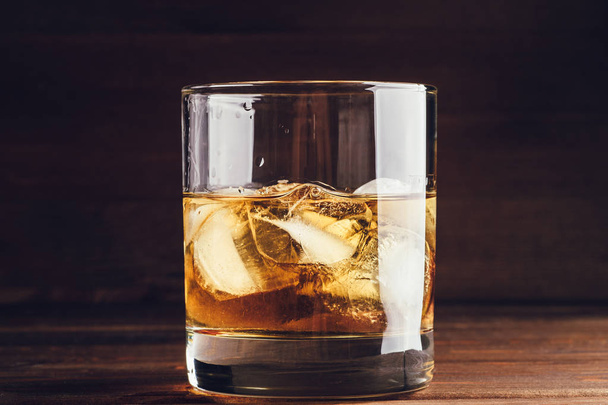 Whiskey glas met ijsblokjes op houten achtergrond - Foto, afbeelding