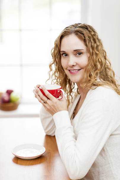 Smiling woman holding red coffee cup - Fotografie, Obrázek