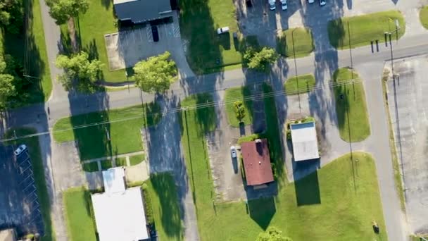 Vista aérea de uma típica área suburbana americana mostrando uma mistura de espaços residenciais, comerciais e naturais conectados por calçadas a ruas e estradas de campo com faixas de espaços para parques de estacionamento, gramados, árvores, arbustos e outras plantações
. - Filmagem, Vídeo