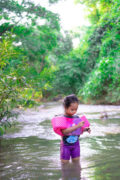 маленькая азиатская девочка с надувными рукавами, играющая на природе
 - Фото, изображение