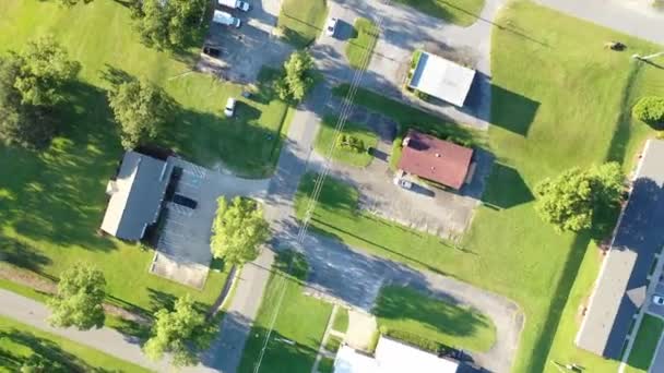 Een luchtfoto van een typisch Amerikaans suburbane gebied met een mix van residentiële, commerciële en natuurlijke ruimtes verbonden door opritten naar straten en landweggetjes met ruimten voor parkeergarages, gazons, bomen, struiken en andere plantage. - Video