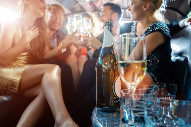 Женщины и мужчины празднуют выпивкой в лимузине
 - Фото, изображение