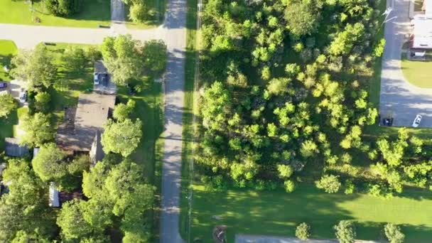 駐車場、芝生、木、茂み、その他のプランテーションのためのスペースの広がりを持つ道路や田舎道への車道で接続された住宅、商業、自然空間のミックスを示す典型的なアメリカの郊外地域の航空写真. - 映像、動画
