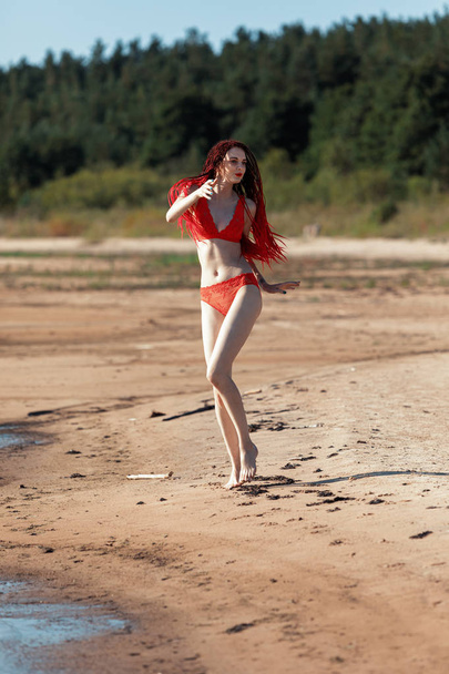 Chica en un traje de baño rojo en la playa
 - Foto, Imagen