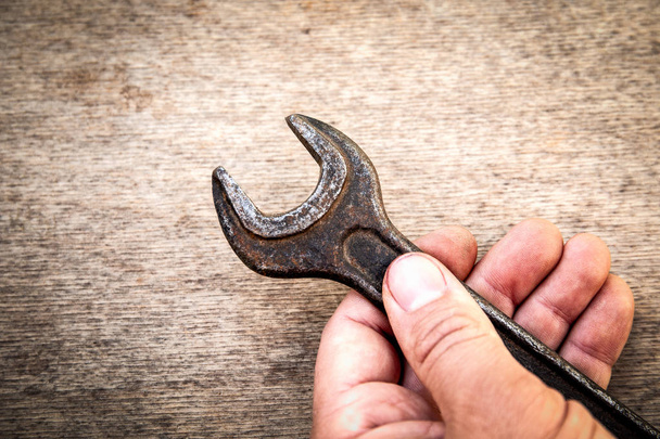 Starý a rezavý klíč v ruce na dřevěném pozadí - Fotografie, Obrázek