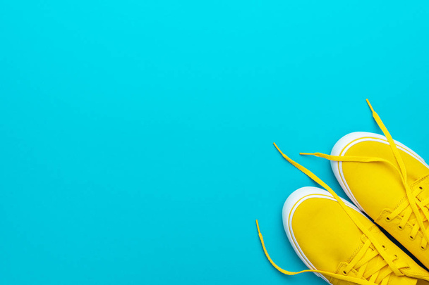 Flat lay minimalist photo of yellow sneakers with untied shoelaces - Foto, imagen