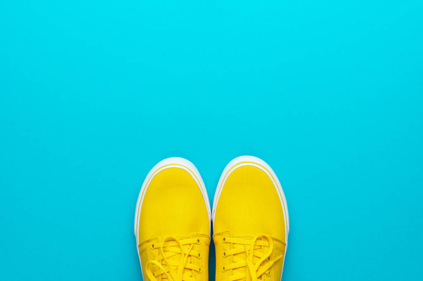 Pair of yellow sneakers on turquoise blue background with copy space - Foto, Bild