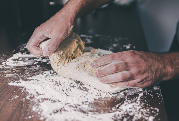 小麦粉のキッチンカウンターに酵母生地を混練する男の手 - 写真・画像