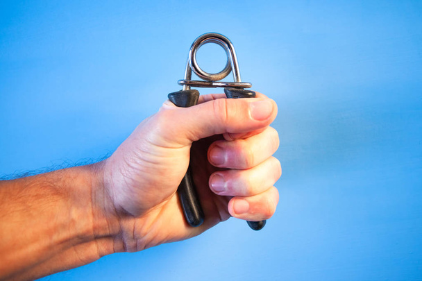an expander for training the arm in a man's clenched fist - Foto, Imagem