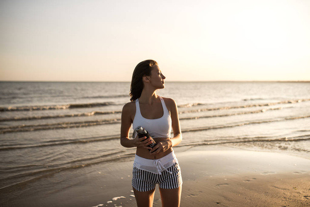 Happy gondtalan sporgyan nő élvezi gyönyörű naplemente a tengerparton - Fotó, kép