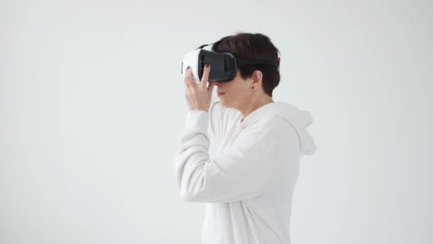 Mulher de meia-idade em uma camisola branca assistindo a um filme com óculos de realidade virtual. O conceito de futurismo e novas tecnologias
. - Filmagem, Vídeo