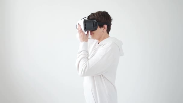 Middle-aged woman in a white sweater watching a movie with glasses of virtual reality. The concept of futurism and new technologies. - Imágenes, Vídeo