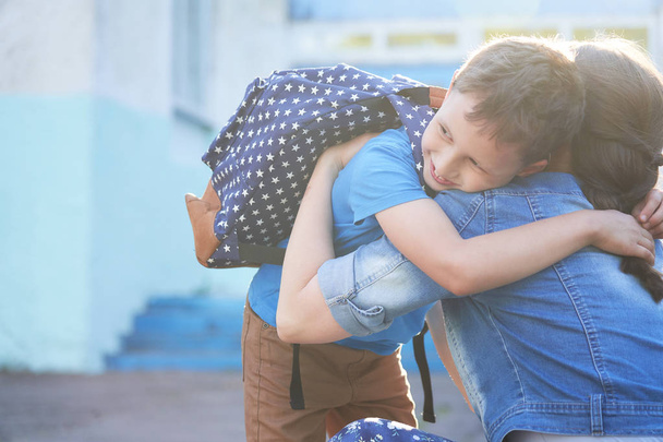 Back to school. Happy mother and son embrace in front of the ele - Фото, изображение