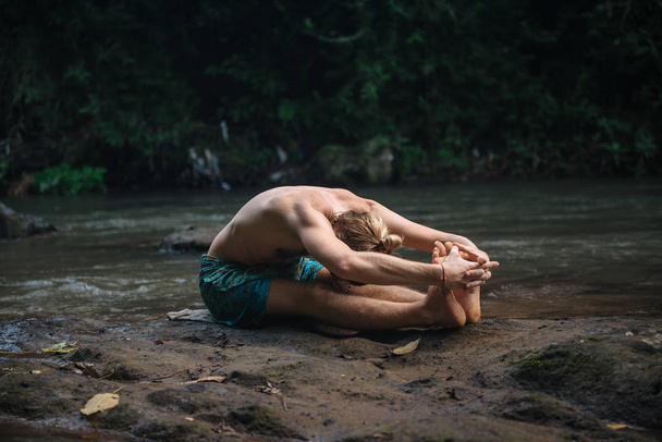 Jóga gyakorlat és meditáció a természetben. A folyó közelében gyakorló ember - Fotó, kép