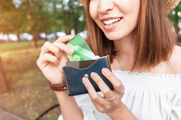 Το κορίτσι βγάζει πλαστικές πιστωτικές κάρτες από την τσάντα της. Οι νέοι επιλέγουν ηλεκτρονικό χρήμα σε τραπεζικό λογαριασμό εκτός μετρητών και όχι σε μετρητά - Φωτογραφία, εικόνα