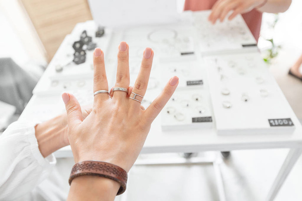 Una mujer probándose un anillo de joyería en la tienda. Tienda de lujo y concepto de compras
 - Foto, Imagen