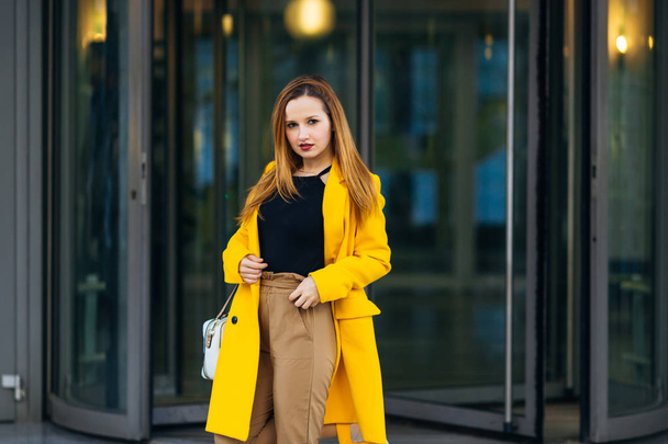 Stile street. ragazza in un cappotto giallo guardando nella fotocamera su
  - Foto, immagini