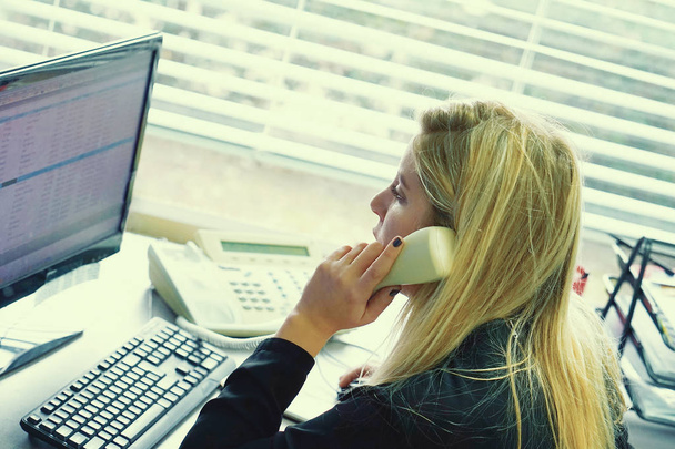Woman sitting at her desk working and answering a phone call. - Photo, Image