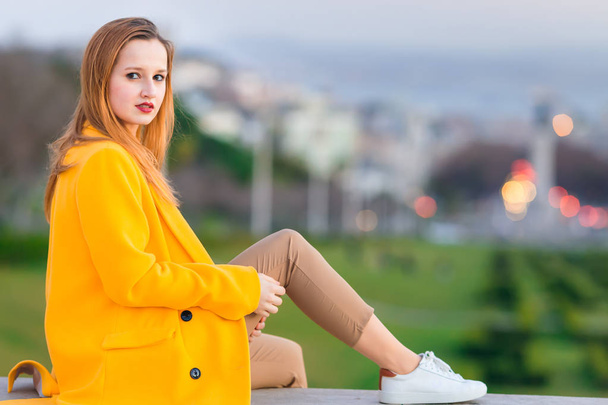 Девушка в желтом пальто смотрит на камеру и позирует против й
 - Фото, изображение