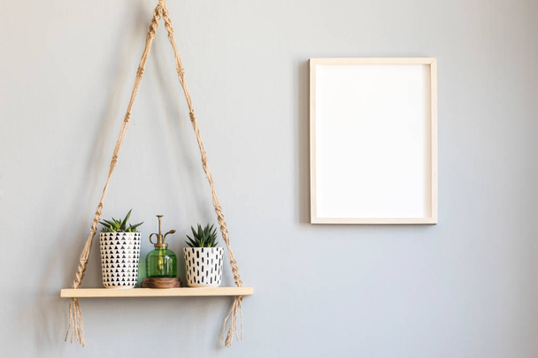 Stylish and minimalistic scandinavian interior with mock up poster frame and hanging wooden shelf with beautiful succulents in hipster pots and green sprinkler. Modern home decor. Template. - Zdjęcie, obraz