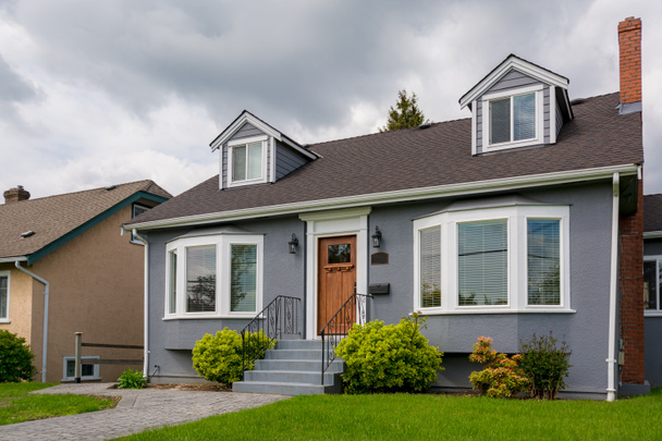 Средний жилой дом с зеленой лужайкой в облачный день в Канаде
 - Фото, изображение
