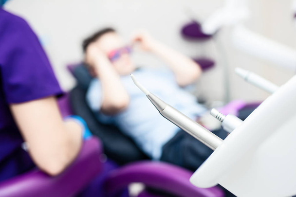 Consultorio dental borroso. Las herramientas están en primer plano. Un chico con gafas en la silla dental
 - Foto, imagen
