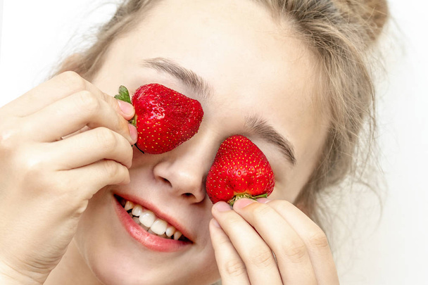 Yeux de fraise. Belle jeune femme tenant des fraises dans les yeux comme des jumelles. Concept de mode de vie sain
.  - Photo, image