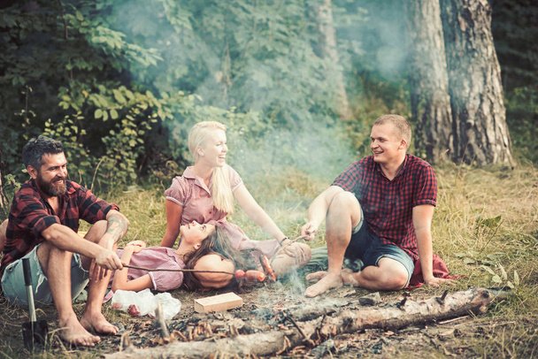 Friends on campsite with sausages sticks in forest - Foto, Imagen