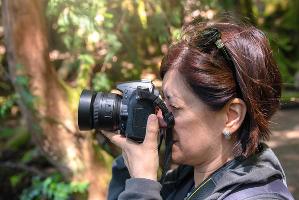 Portret kobiety profesjonalny fotograf robienia zdjęć w parku. Squamish, BC, Kanada. - Zdjęcie, obraz