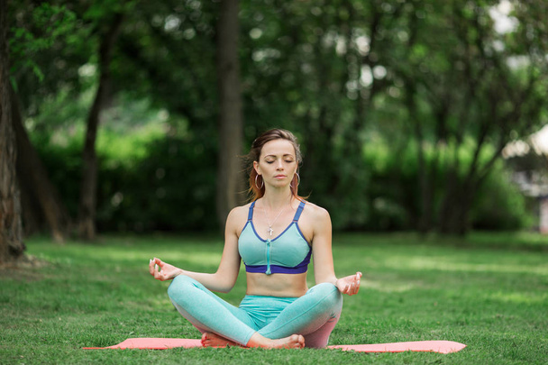 Mujer bonita joven haciendo yoga y estiramiento en el parque verde, hora de verano
 - Foto, Imagen