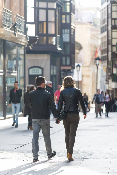 Ζαμόρα, Ισπανία-1 Νοεμβρίου 2016: ένα ζευγάρι περπατάει χέρι-χέρι σε ένα δρόμο στην πόλη, μια ηλιόλουστη μέρα του φθινοπώρου. - Φωτογραφία, εικόνα