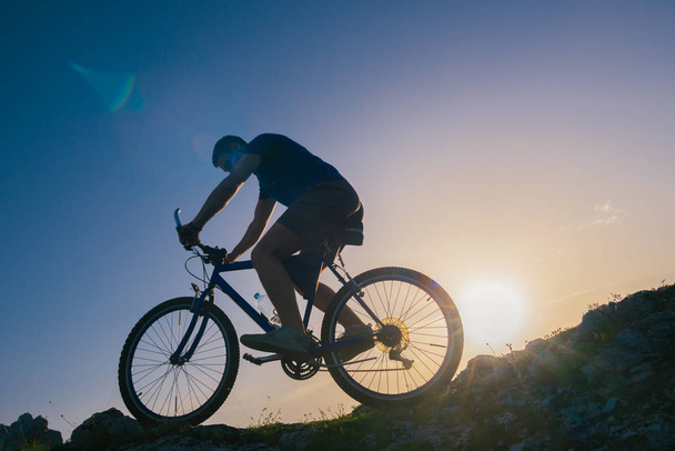 Silueta mužského cyklistického bikera na kole do kopce o - Fotografie, Obrázek