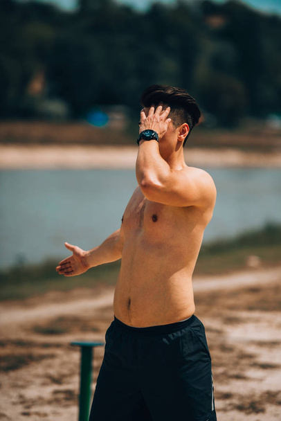 Fitness shirtless man stretching his leg muscles outdoors - Fotó, kép