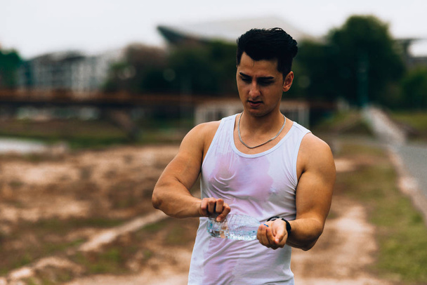 Jonge man houden fitness fles met water - Foto, afbeelding