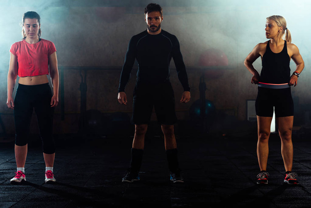 Group of three bodybuilders in crossfit gym - Фото, изображение