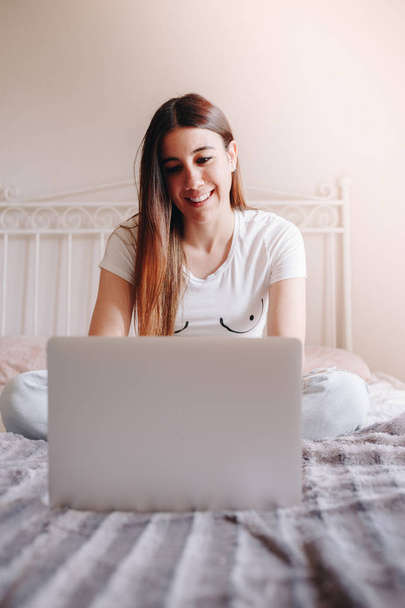 beautiful young woman smiling and writing on her laptop - Foto, Imagen