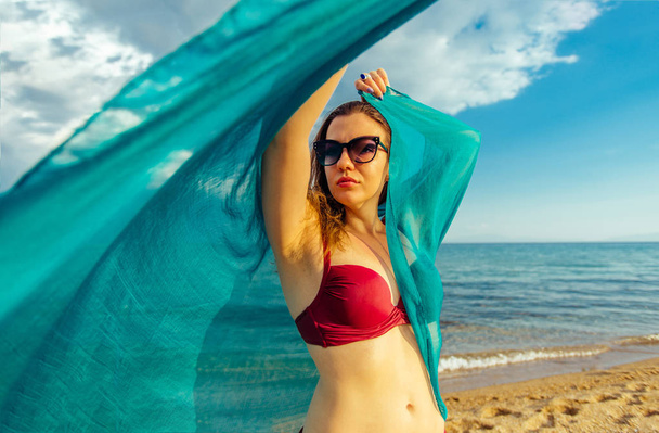 Caucasian woman with blue scarf enjoying freedom on the beach - Foto, Bild