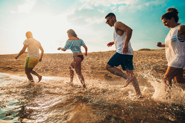 Grupo de personas corriendo en la playa en el mar
 - Foto, Imagen