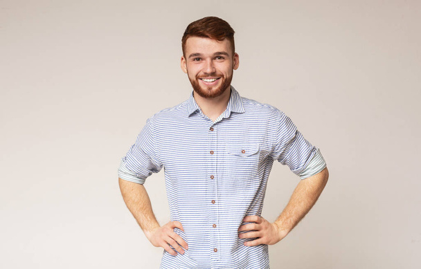 Портрет улыбающегося парня с руками на бедрах
 - Фото, изображение