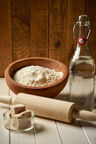 Ingredienti per la farina di pasta per pizza con olio d'oliva e lievito su tavola di legno
 - Foto, immagini