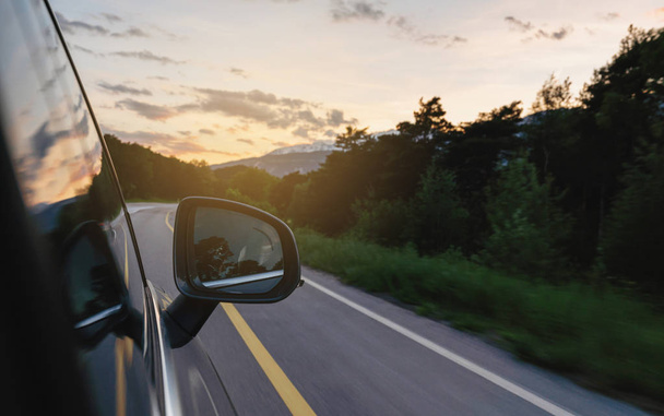 Rijden op landweg in de zomer bij zonsondergang, zijvleugel spiegel uitzicht - Foto, afbeelding